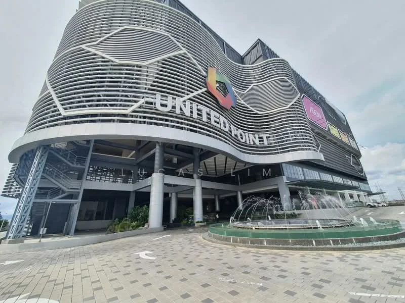 Exterior type: shopping mall; features: modern facade with curved design, metal cladding, large glass windows, water fountain at entrance, paved walkway, landscaped greenery, multiple signage panels, multi-storey structure, open-air parking area; style: modern.