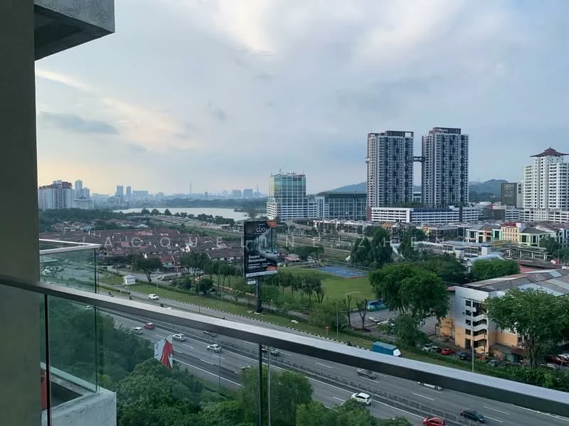 Exterior type: high-rise condominium; features: city skyline view, balcony with glass railing, surrounding greenery, nearby urban development, highway visible in foreground, mixed-use buildings in background; style: modern.