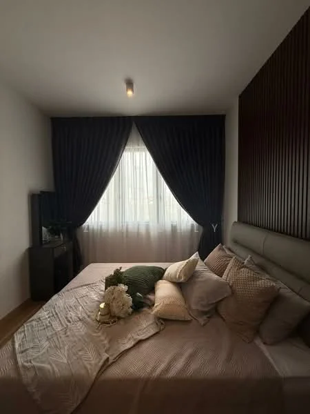 Bedroom features: queen-size bed, upholstered headboard, decorative throw pillows, bedside table, table lamp, floor-to-ceiling window, sheer curtains, dark curtains, wooden flooring, accent wall with wood paneling, wall-mounted TV, area rug; style: modern.