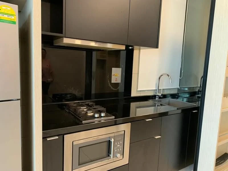 Kitchen features: black cabinetry, black granite countertop, stainless-steel sink, chrome pull-down faucet, built-in microwave, freestanding range oven, 4-burner gas hob, exhaust hood, tile backsplash, recessed downlights; style: modern.