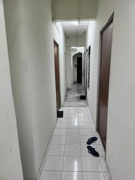 Hallway features: white painted walls, ceramic tile flooring, wooden doors, overhead lighting, sliding door, door frames, baseboards, two pairs of slippers on the floor.