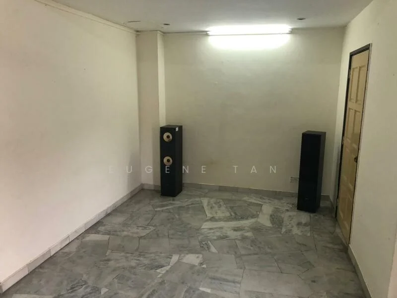 Room features: white painted walls, marble flooring, two black speakers, single door, fluorescent ceiling light.