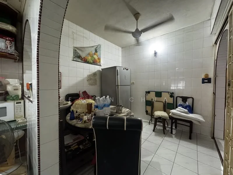 Kitchen features: white tiled walls, white tiled flooring, ceiling fan, stainless-steel fridge, microwave, round dining table, 4 dining chairs, wooden shelving, decorative wall art, plastic water bottles, kitchen cabinets, countertop, open shelving with kitchen items.