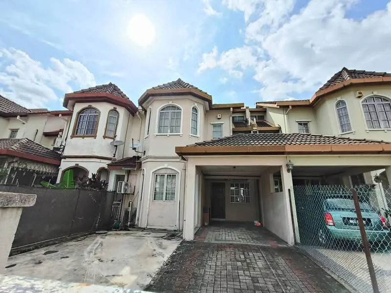 Exterior type: semi-detached house; features: cream painted facade, pitched tile roof, two-storey structure, car porch with awning, manicured lawn, brick-paved driveway, fenced perimeter, air conditioning unit visible, windows with grills, gabled roof design; style: modern.