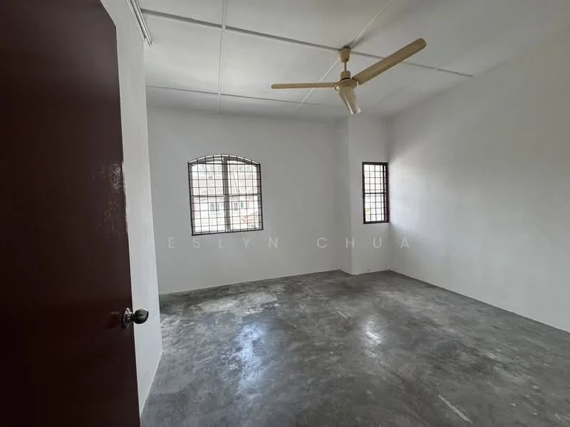 Room features: white painted walls, concrete flooring, ceiling fan, two small windows with metal grilles, plain ceiling, no visible furniture; style: minimalist.