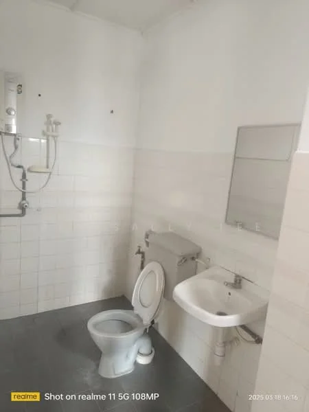 Bathroom features: white tiled walls, grey floor tiles, one-piece toilet, wall-mounted sink, framed mirror, shower with wall-mounted faucet, handheld shower head, water heater, toilet paper holder, soap dispenser.