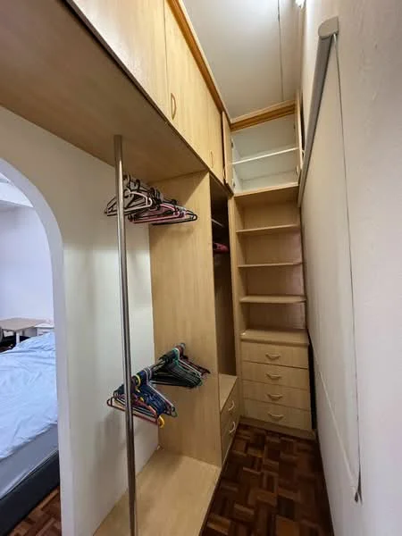 Room features: built-in wardrobe with wooden finish, open shelving, hanging rods for clothes, drawers for storage, wooden flooring, white walls, natural light from window, minimalist design; style: modern.