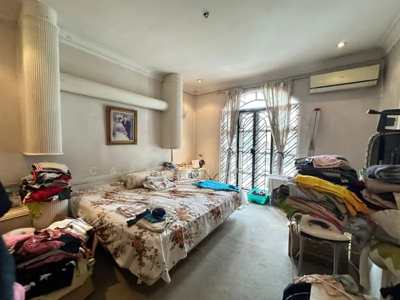 Bedroom features: queen-size bed with floral bedding, upholstered headboard, wall-mounted air conditioning unit, floor-to-ceiling windows with security bars, sheer curtains, light-colored painted walls, carpet flooring, decorative wall columns, framed artwork on wall, clothes piled on bed and chair, white bedside table, plastic storage basket.