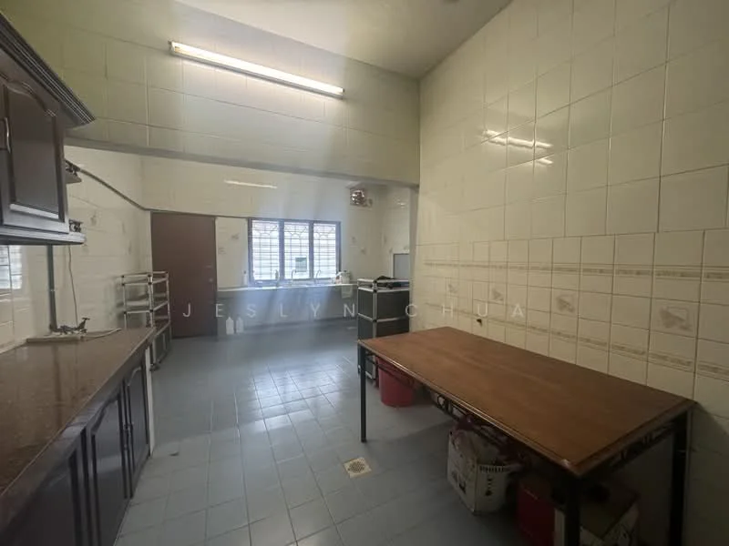 Kitchen features: white tiled walls, grey tiled flooring, brown wooden cabinetry, granite countertop, stainless-steel sink, freestanding gas stove, oven, window with metal grille, table with metal legs, storage shelves, refrigerator.