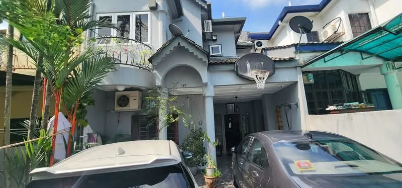 Exterior type: semi-detached house; features: grey painted facade, arched entrance, balcony with railing, paved driveway, two parked cars, outdoor plants, wall-mounted air conditioning unit, basketball hoop, roof overhang, multiple satellite dishes, manicured landscaping; style: modern.