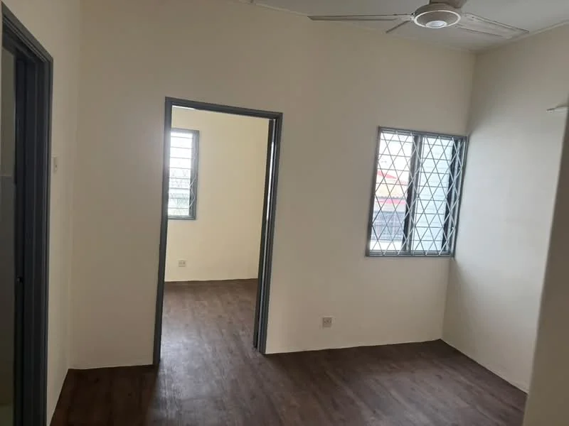 Room features: light wood laminate flooring, white painted walls, ceiling fan, two windows with security grills, doorway leading to another room.