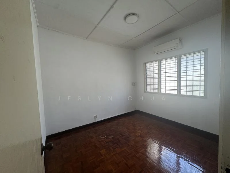 Room features: white painted walls, parquet wood flooring, 1 wall-mounted split AC, 2 windows with grilles, ceiling light, door with knob.