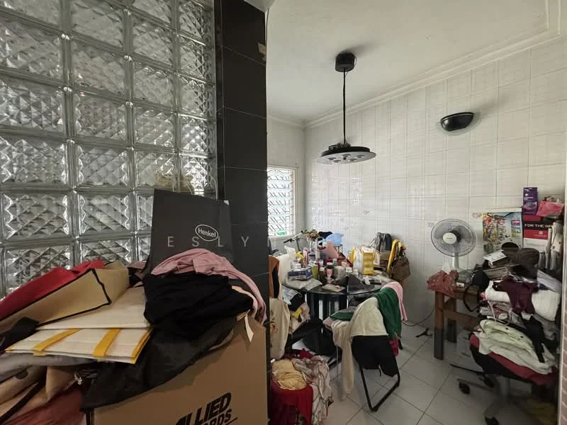 Room features: glass block wall, white tiled walls, white ceiling, black pendant light, wall-mounted light fixture, tile flooring, cluttered workspace, folding table, fan, various boxes and fabric piles.