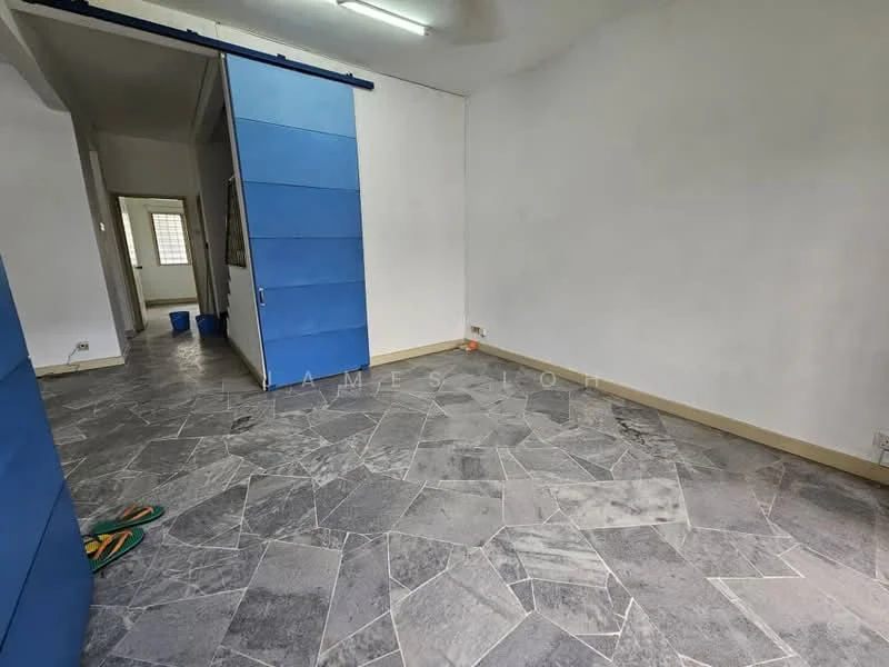 Room features: grey patterned flooring, white painted walls, blue sliding doors, ceiling lights, window with grid, corner with bucket, empty space.