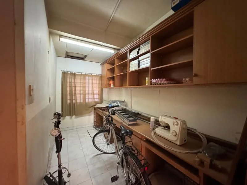 Laundry features: white painted walls, tile flooring, wooden shelving, window with sheer curtains, sewing machine, bicycle, storage basket, long countertop, light fixture on ceiling.