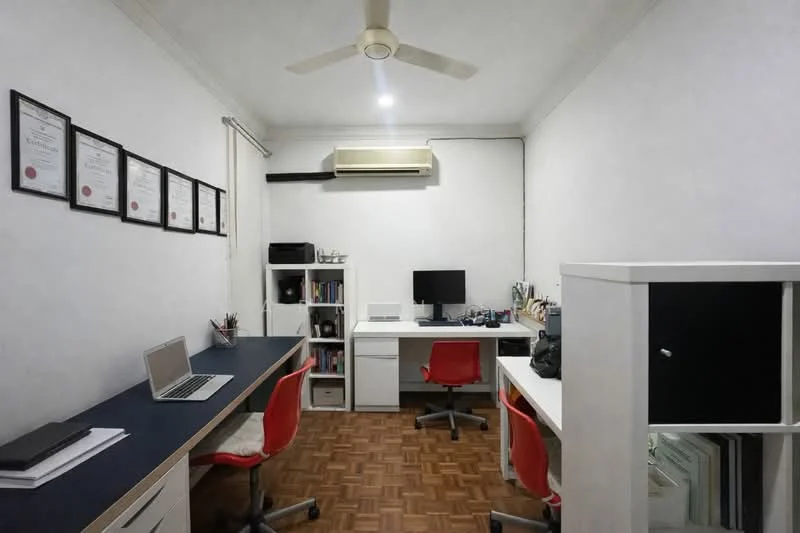Study features: white painted walls, wooden flooring, 5-blade ceiling fan, 1 wall-mounted split AC, 2 study desks with blue tops, 2 red office chairs, computer monitor, laptop, shelves with documents, framed certificates on wall, storage cabinet; style: modern.