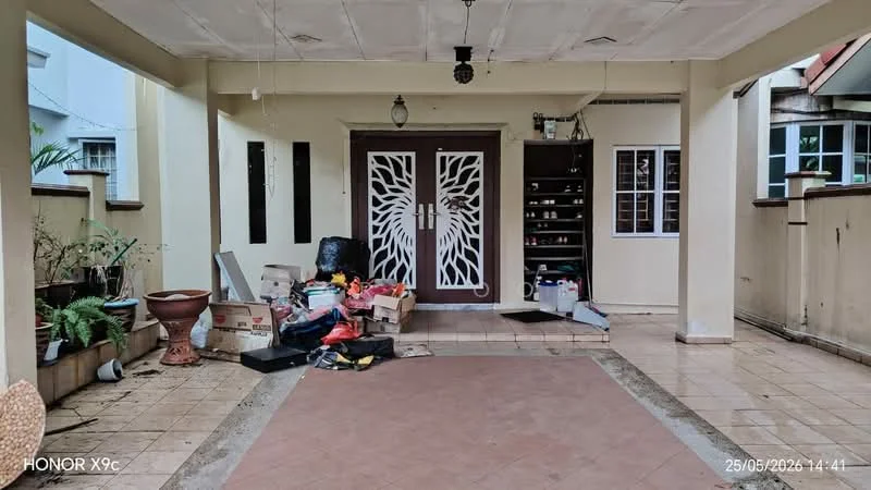 Exterior features: covered porch, decorative front door with intricate design, tile flooring, potted plants, storage shelves, boxes and miscellaneous items, light fixture, wall with window openings.