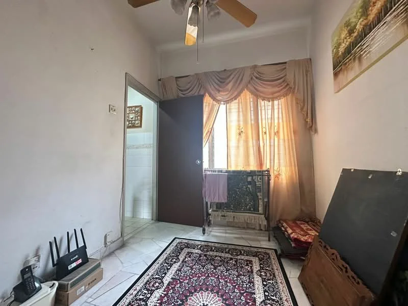 Room features: white painted walls, marble tile flooring, ceiling fan, window with sheer curtains, decorative wall art, area rug with intricate pattern, wooden door, folding clothes rack.
