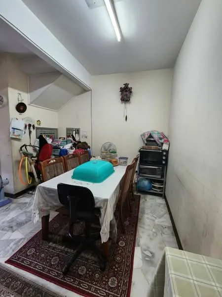Dining features: dining table with white tablecloth, wooden dining chairs, area rug with geometric pattern, ceiling light fixture, marble flooring, wall-mounted fan, kitchenette area visible in background, storage cabinet, decorative wall hanging.