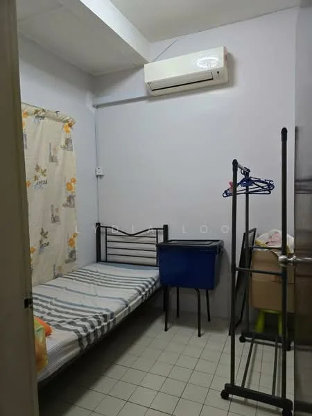 Bedroom features: single bed with metal frame, striped bed linens, wall-mounted air conditioning unit, light grey painted walls, tiled flooring, curtains with floral pattern, clothes rack, blue plastic storage bin, wooden cabinet, green plastic chair.