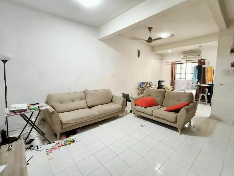 Living features: beige fabric 3-seater sofa, beige fabric 2-seater sofa, red throw pillows, wooden coffee table, white tiled flooring, white painted walls, ceiling fan, window with sheer curtains, air conditioning unit, floor lamp, decorative items on table, scattered papers on floor; style: minimalist.