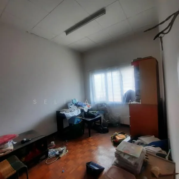 Room features: light-colored painted walls, wooden flooring, window with sheer curtains, ceiling light fixture, cluttered space with various items, desk with items on it, storage cabinet, boxes and bags scattered on the floor.