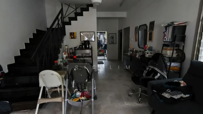 Room features: grey tiled flooring, white painted walls, black metal staircase, ceiling fan, large window with sheer curtains, dining table with chairs, black office chair, bookshelf with various items, sofa, decorative wall mirrors, kitchenette area with countertop, appliances on countertop; style: modern.