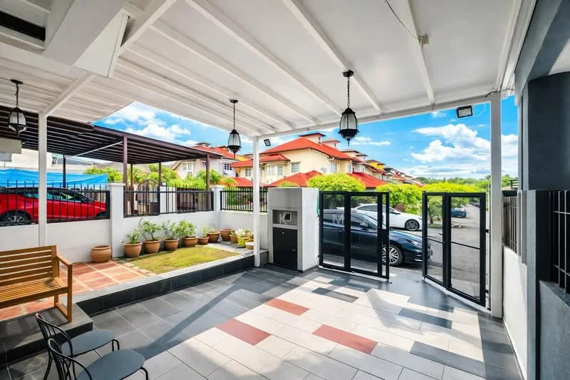 Exterior type: linked terrace house; features: covered porch with roof, grey tiled flooring, white painted walls, black metal gate, landscaped garden with potted plants, outdoor seating area with wooden bench, two pendant lights, driveway with interlocking pavers, surrounded by greenery, car parked in driveway, street view with neighboring houses; style: modern.