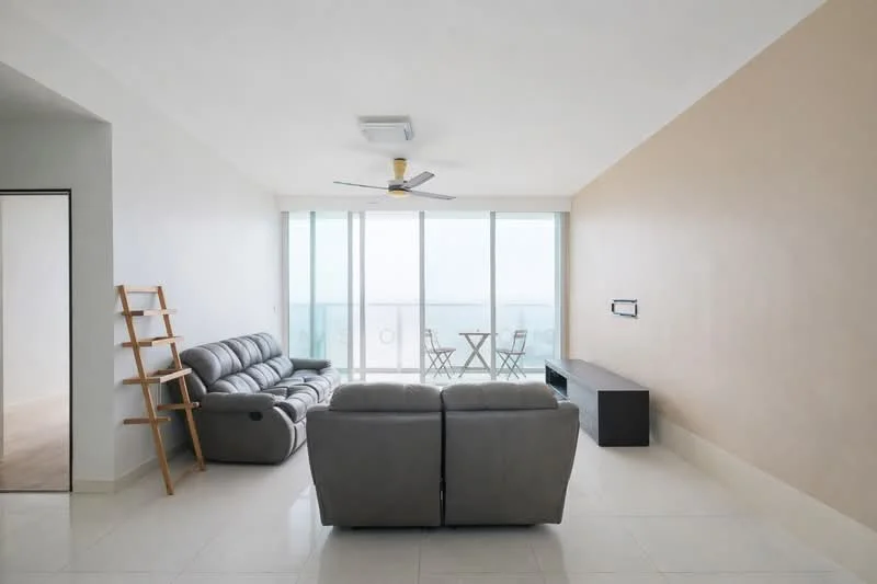 Living features: grey leather sectional sofa, 2-seater sofa, coffee table, wall-mounted TV console, ceiling fan with light, large floor-to-ceiling windows, neutral painted walls, glossy tile flooring, small dining table with two chairs, decorative ladder shelf; style: modern; view: sea.
