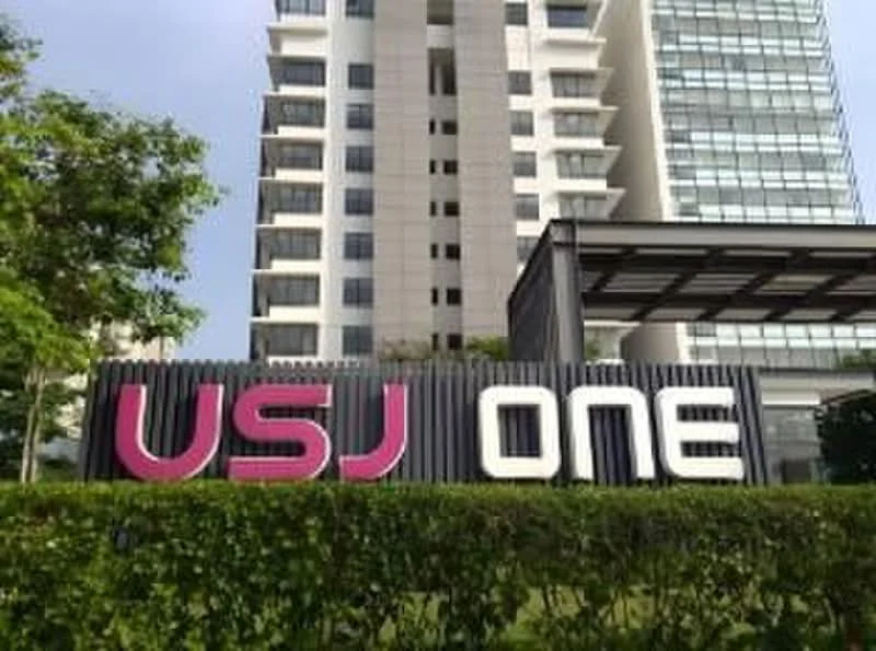 Exterior type: high-rise condominium; features: modern facade, glass curtain wall, landscaped garden, prominent signage, manicured hedges, outdoor seating area, covered entrance, surrounded by greenery; style: contemporary.