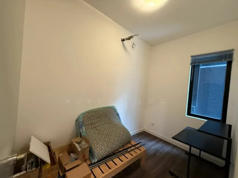 Room features: white painted walls, wooden flooring, single window with blinds, ceiling light fixture, mattress on wooden platform, cardboard boxes, small desk.