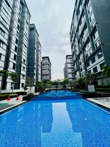 Exterior type: high-rise condominium; features: swimming pool with blue mosaic tiles, surrounded by landscaped gardens, multiple high-rise buildings, concrete pathways, potted plants along the poolside, lounge chairs by the pool, water features, trees providing shade, modern architectural design, clear sky, safety cones near the pool area; style: modern.