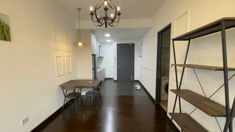 Dining features: dark wood flooring, white painted walls, chandelier with multiple bulbs, pendant light above dining table, round dining table, 4 metal dining chairs, open shelving unit, door leading to hallway, door leading to kitchen, wall-mounted artwork, recessed ceiling lights; style: modern. Kitchen features: white cabinetry, stainless-steel appliances, black countertop, open layout to dining area; style: modern.