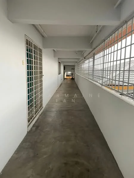 Hallway features: concrete flooring, white painted walls, metal grilles on windows, overhead lighting, long corridor layout, exposed ceiling, natural light from windows, doorways leading to rooms; style: minimalist.