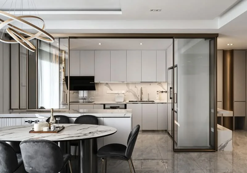 Kitchen features: marble countertop, white cabinetry, built-in oven, stainless-steel fridge, stainless-steel sink, chrome pull-down faucet, ceramic tile flooring, recessed downlights, glass partition, modern pendant lighting, grey backsplash, open shelving, round dining table, upholstered dining chairs; style: modern.
