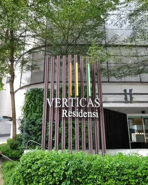 Exterior type: high-rise condominium; features: modern facade, glass curtain wall, wooden slatted feature wall, landscaped greenery, signage with name 'VERTICAS Residensi', surrounding plants, entrance area with pathway; style: modern.