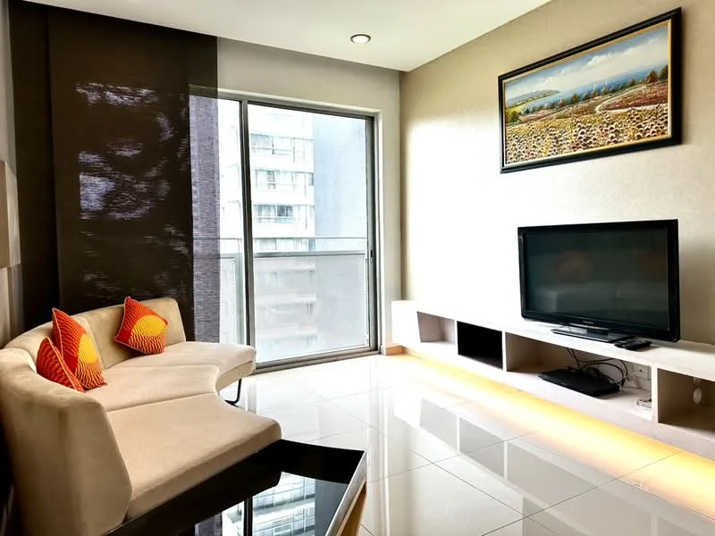 Living features: white sofa with curved design, orange decorative cushions, black coffee table, wall-mounted TV, TV console with storage, large glass sliding door, floor-to-ceiling windows, glossy tile flooring, recessed lighting, light-colored wall with artwork, sheer curtains; style: modern; view: city.
