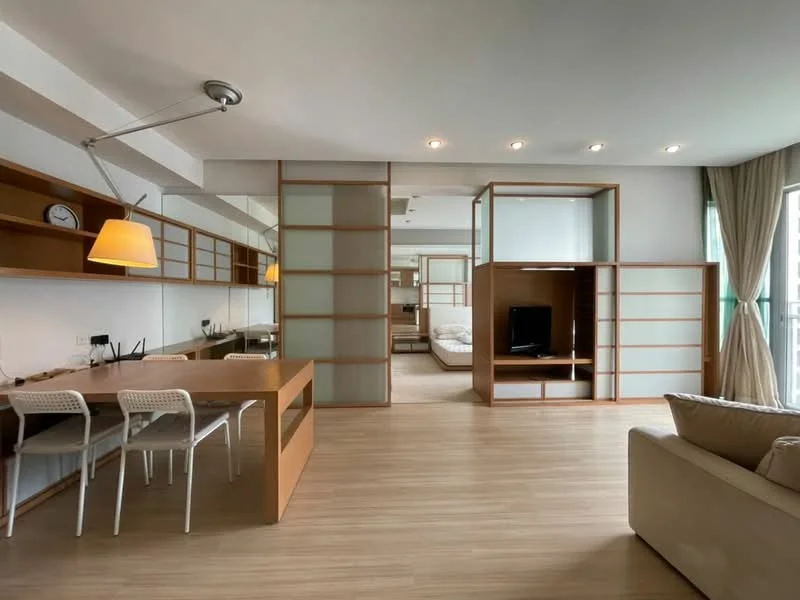 Living features: wooden flooring, floor-to-ceiling windows, light beige sofa, wooden coffee table, wall-mounted TV, built-in shelving, recessed downlights, decorative wall clock, open-plan layout, curtains, study desk, white dining chairs, pendant lamp; style: modern. Room features: queen-size bed, built-in wardrobe, sliding glass door.