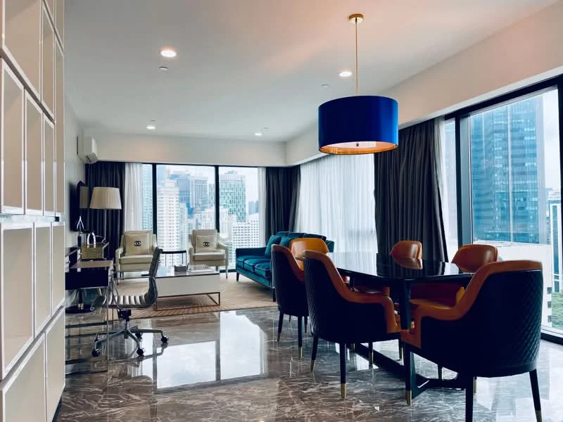 Living features: floor-to-ceiling windows, grey curtains, blue pendant light, marble flooring, green velvet sofa, two armchairs with patterned upholstery, glass coffee table, dining table with black surface, four upholstered dining chairs, decorative wall shelving, air conditioning unit, city skyline view; style: modern; view: city.