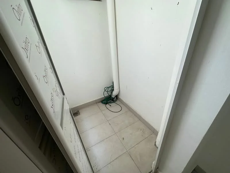 Room features: white painted walls, tile flooring, corner space, visible plumbing, electrical cord on floor.