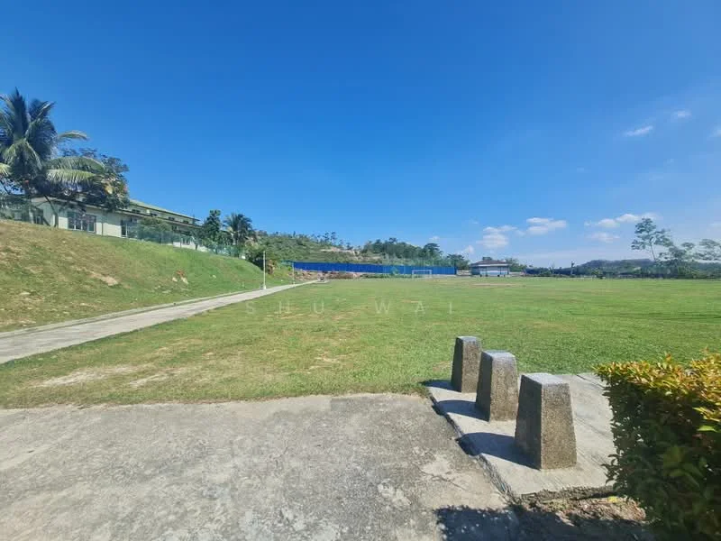 Exterior type: landscape garden; features: manicured lawn, paved walkway, surrounded by palm trees, open field, clear blue sky, distant hills, fenced area, greenery in background; style: tropical-modern.