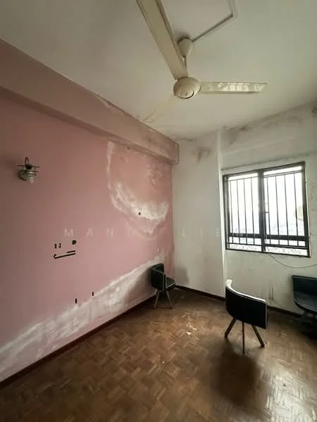 Room features: pink painted walls, exposed concrete ceiling, wooden parquet flooring, 1 ceiling fan, 1 window with metal bars, 2 black chairs.