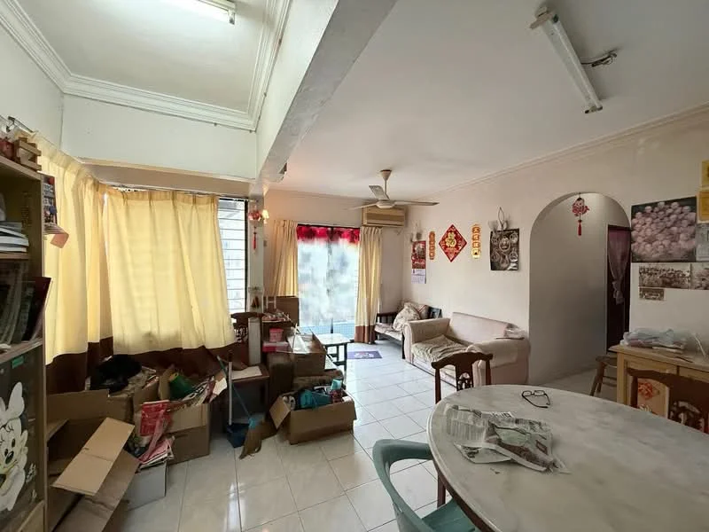 Living features: white painted walls, white tiled flooring, 5-blade ceiling fan, large windows with sheer curtains, sofa in beige, coffee table, dining table with chairs, boxes and clutter, decorative wall art, air conditioning unit.