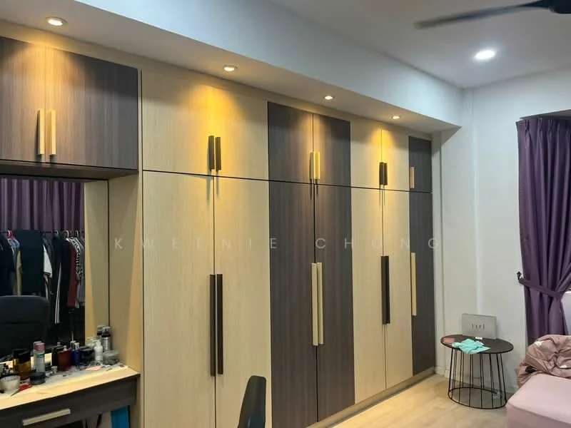Room features: built-in wardrobe with light wood and dark wood panels, multiple cabinet doors, recessed lighting above cabinets, light-colored wooden flooring, purple curtains, vanity table with makeup items, black office chair, wall-mounted fan; style: modern.
