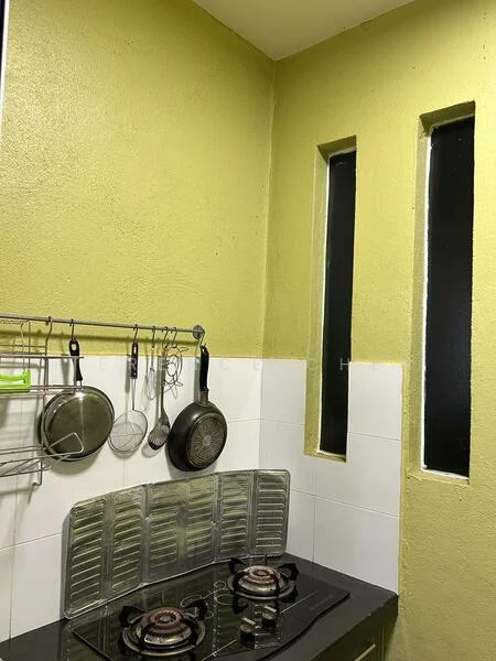 Kitchen features: green painted walls, white tiled backsplash, black countertop, 2-burner gas hob, stainless-steel cooking utensils, hanging rack for utensils, narrow vertical windows, wall-mounted storage rack; style: modern.