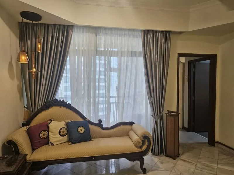 Living features: sofa with ornate wooden frame, cream upholstery on sofa, decorative cushions in various colors, floor-to-ceiling windows, sheer curtains, grey drapes, marble flooring, wall-mounted light fixtures, decorative wall paneling, doorway leading to another room; style: luxury.
