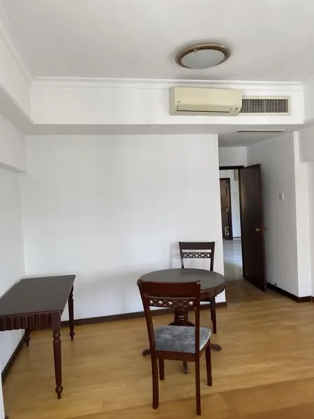 Room features: white painted walls, wooden flooring, ceiling light fixture, wall-mounted split AC, round dining table, wooden dining chairs, doorway leading to another room.