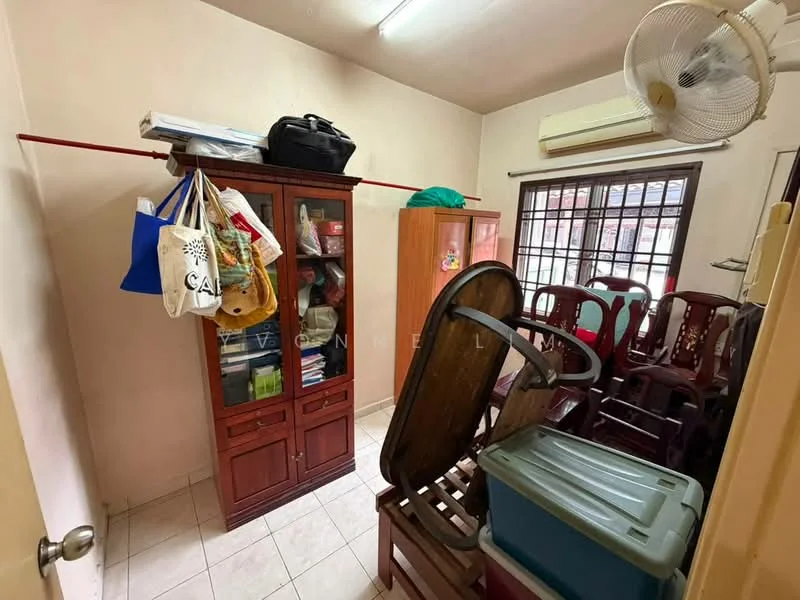 Room features: white painted walls, tile flooring, window with grid pattern, ceiling fan, wooden cabinet, stacked chairs, plastic storage container, various bags, shelves with items.