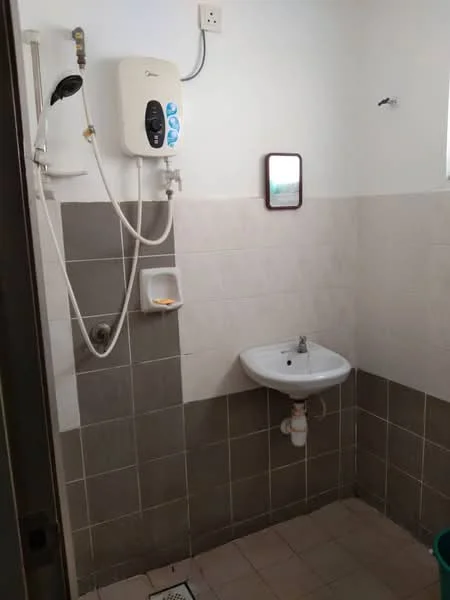 Bathroom features: white ceramic sink, chrome basin mixer faucet, wall-mounted shower heater, grey tiled walls, white tiled walls, ceramic floor tiles, small mirror, drainage grate, shower area, toilet paper holder.