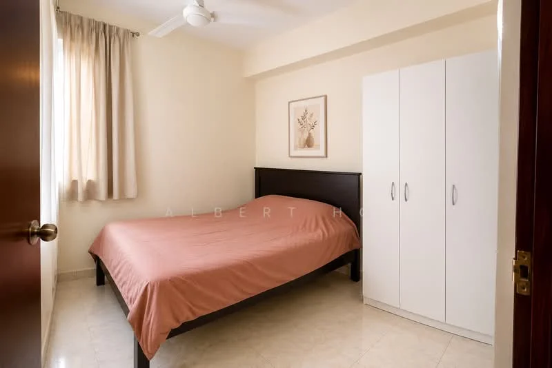 Bedroom features: queen-size bed with beige bedspread, white wardrobe with sliding doors, cream painted walls, marble tile flooring, floor-to-ceiling window with sheer curtains, ceiling fan, decorative wall art, natural light from window; style: modern.